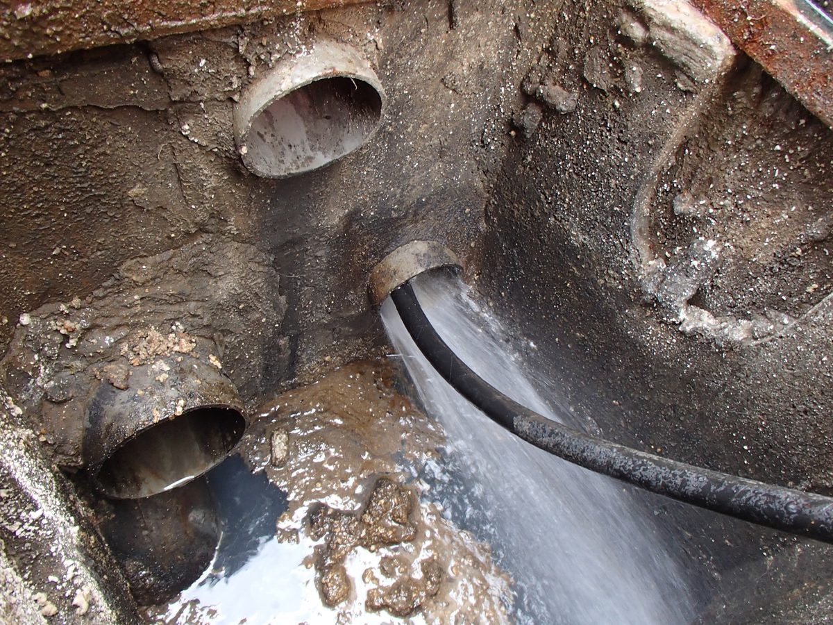 Débouchage par haute pression d'eau dans une chambre de visite ouverte.