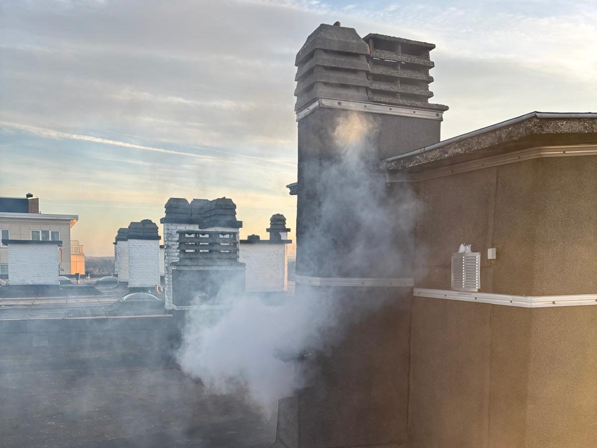 Fumée s'échappant au pied d'une souche de cheminée, sur la toiture plate d'un immeuble, lors d'un test fumigène.