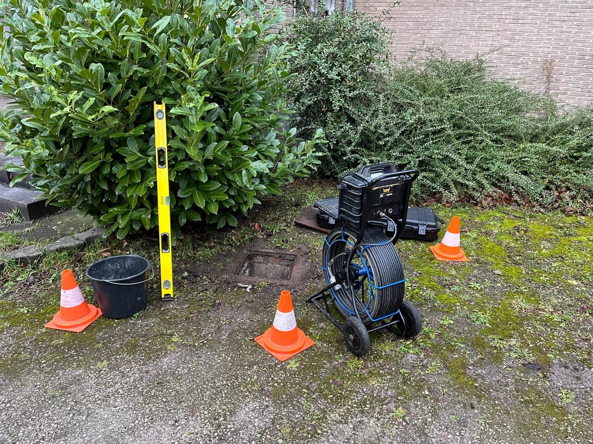 Intervention sur un regard ouvert, matériel de chantier posé à proximité et zone balisée par des cônes.
